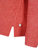 Korallenfarbene Strickjacke mit Spinnennetzmuster und Knopfverschluss.