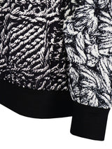 Schwarz-weiße Kapuzenjacke mit Struktur und gerippten Bündchen.