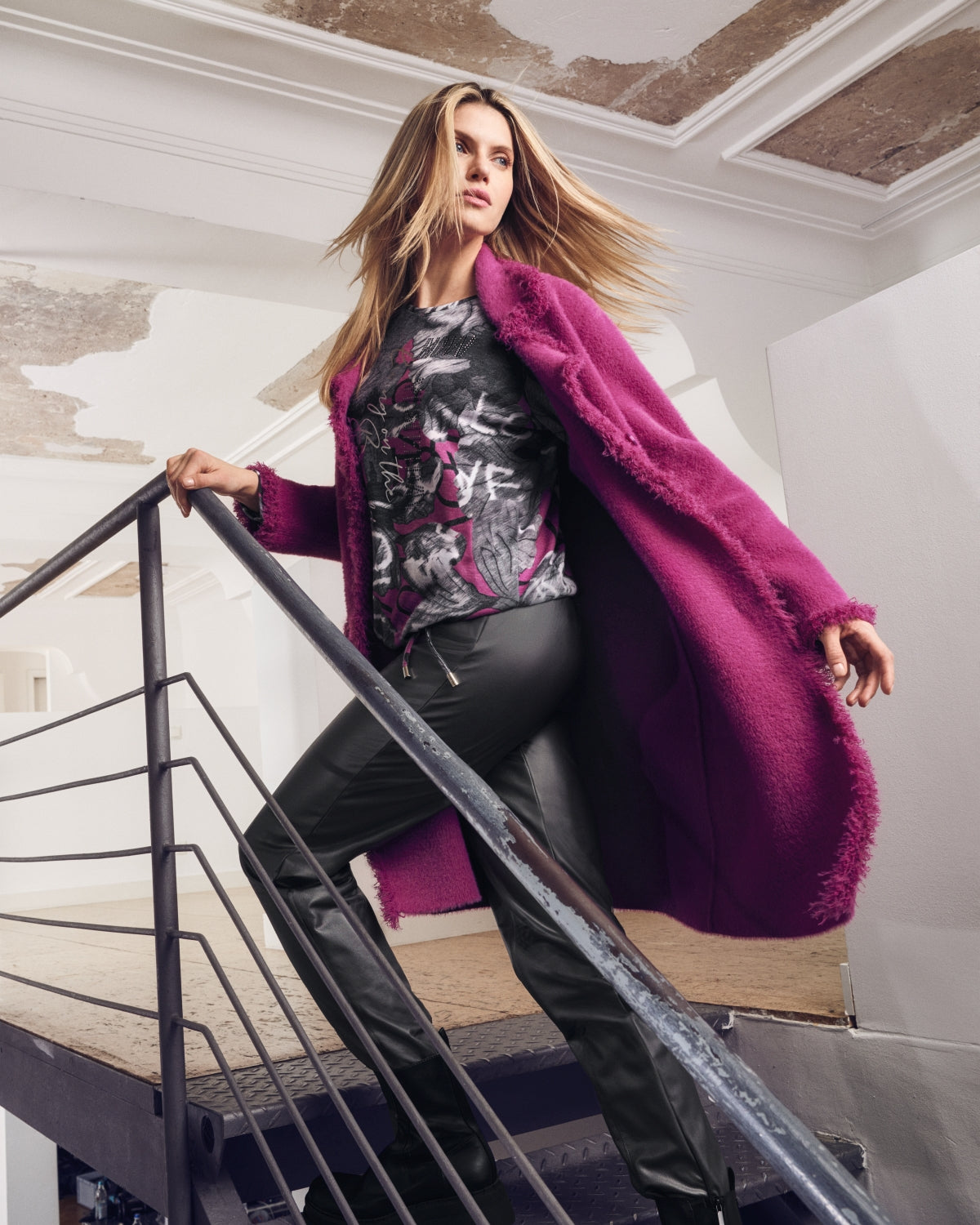 Lange magentafarbene Damenstrickjacke mit schwarzer Lederhose und gemustertem Top.