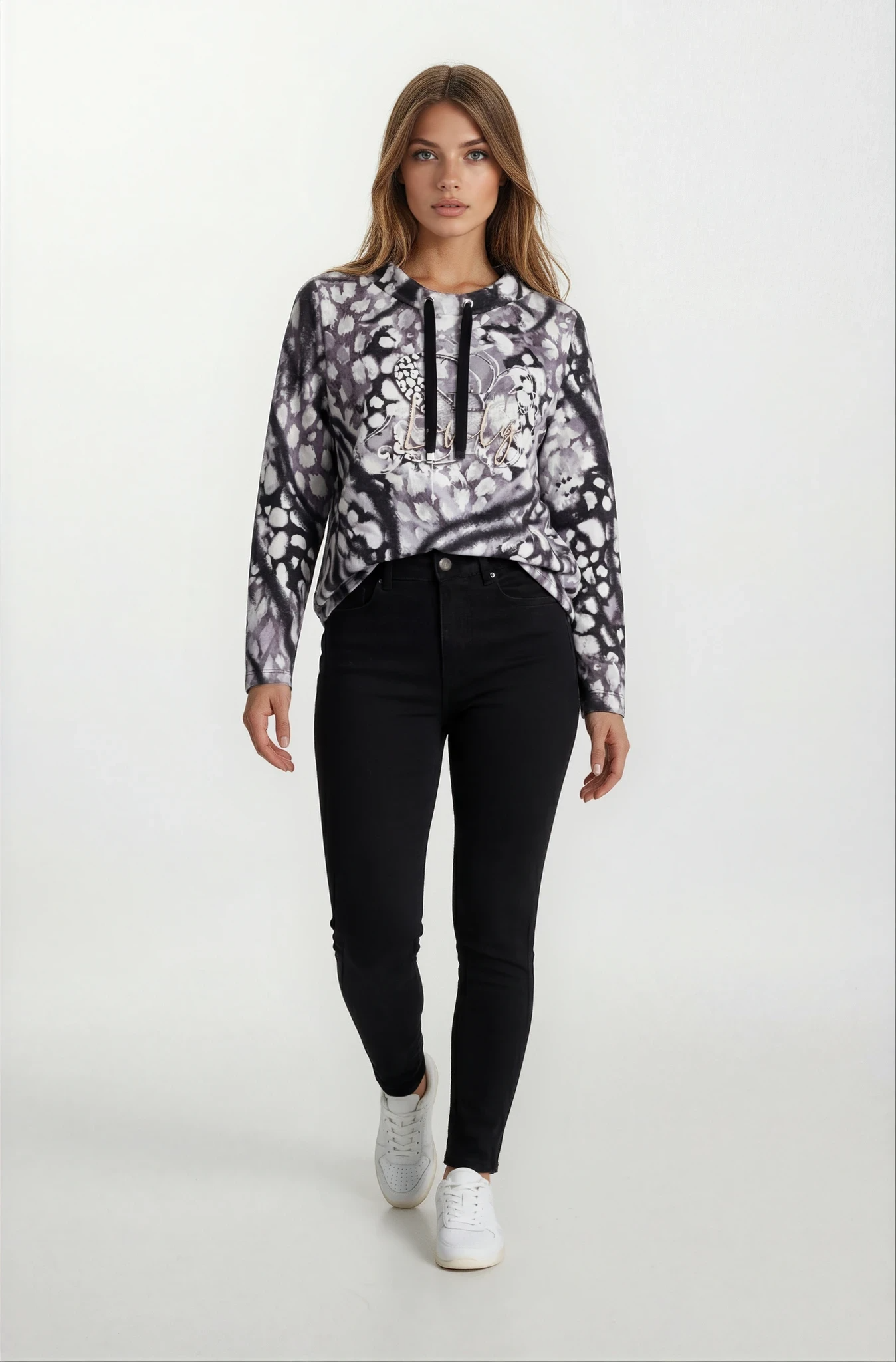 Frau in schwarzem-weiß gemustertem Hoodie mit Floraldesign und Zierbändern