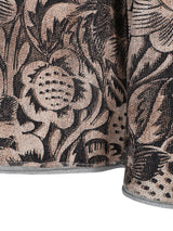 Blumiges Mustergewebe-Kissen mit schwarz-weißem Design auf beigem Hintergrund.