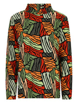 Frau mit grünem Kapuzenpullover mit Reißverschluss, schwarzer Hose und schwarzen Halbschuhen.