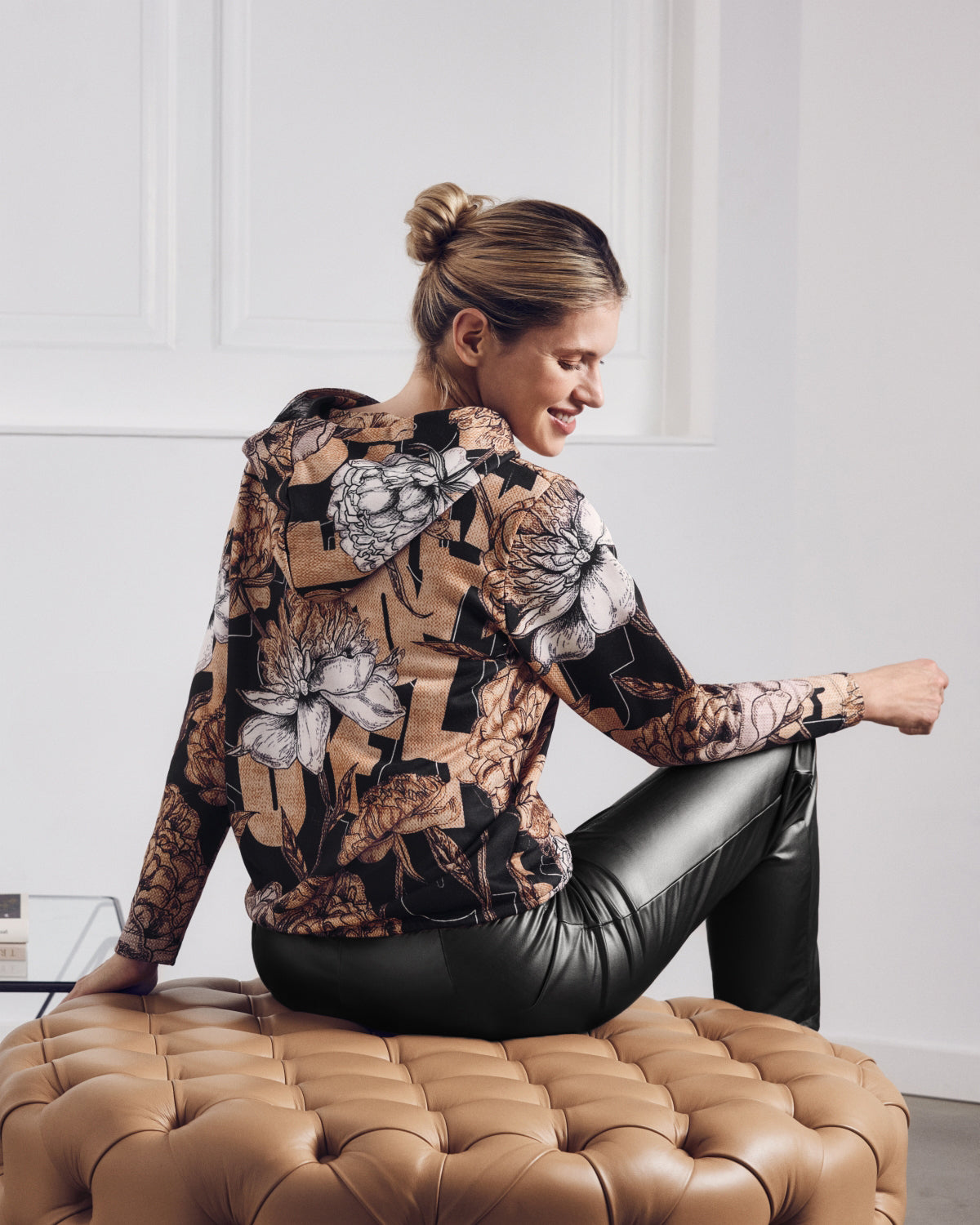 Damen-Kapuzenpulli mit Blumendruck und schwarze Kunstlederhose.