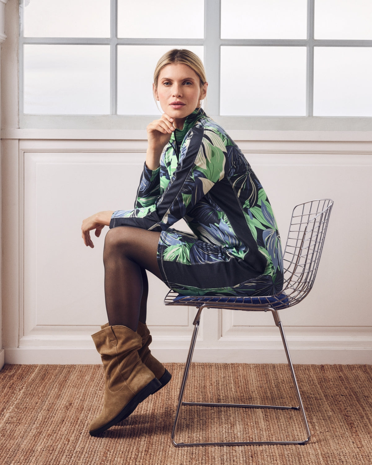 Frau in einem Kleid mit tropischem Muster und braunen Schlabberstiefeln.