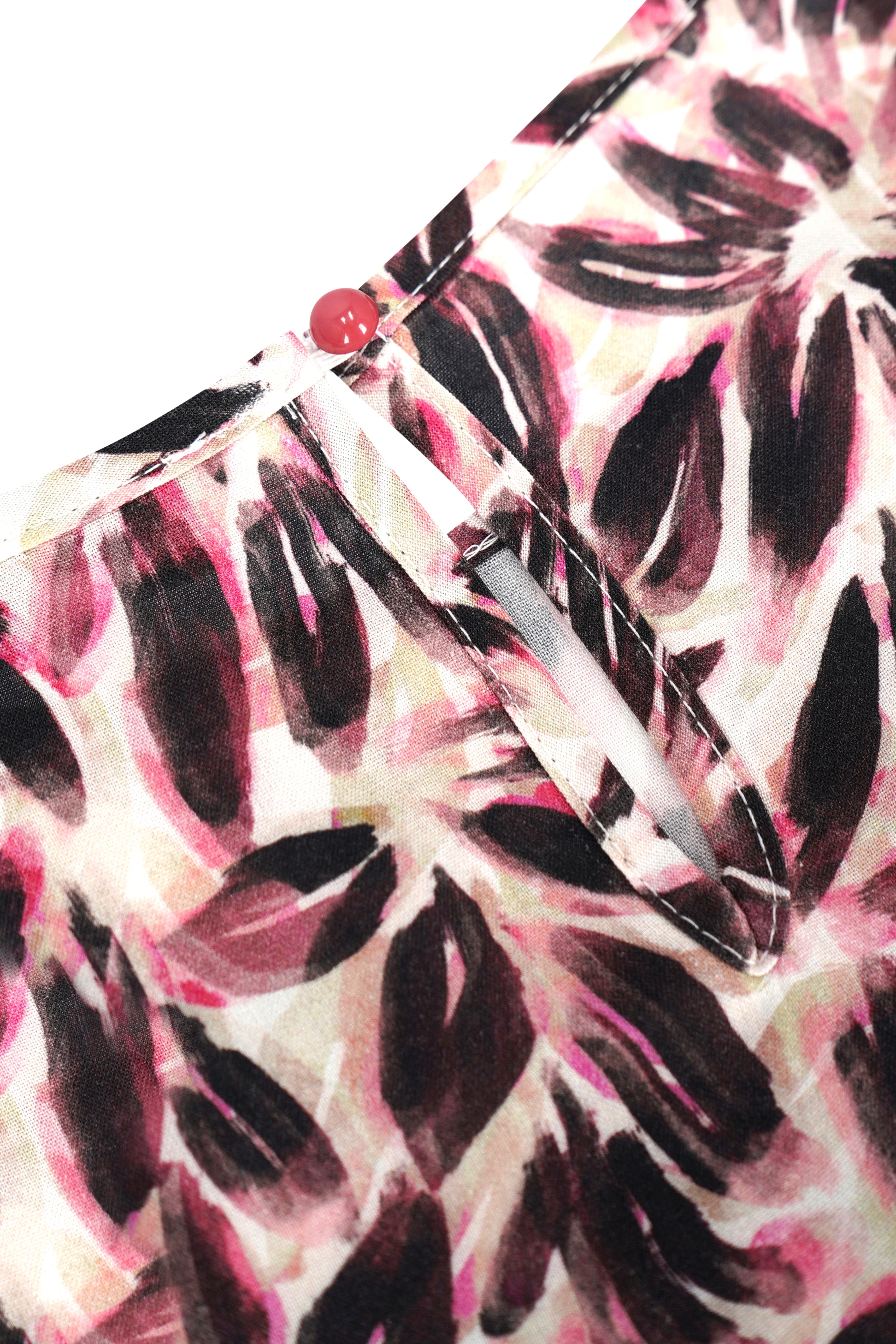 Bluse blütenprint aus rosa und schwarz gemustertem stoff mit rotem knopfverschluss