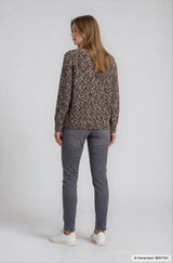 Eine frau trägt einen braun-beigen, locker sitzenden pullover mit jeans 5-pocket für einen lässigen look