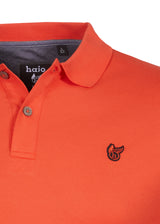 Leuchtend korallenfarbenes Poloshirt mit einem kleinen gestickten Vogel-Logo.