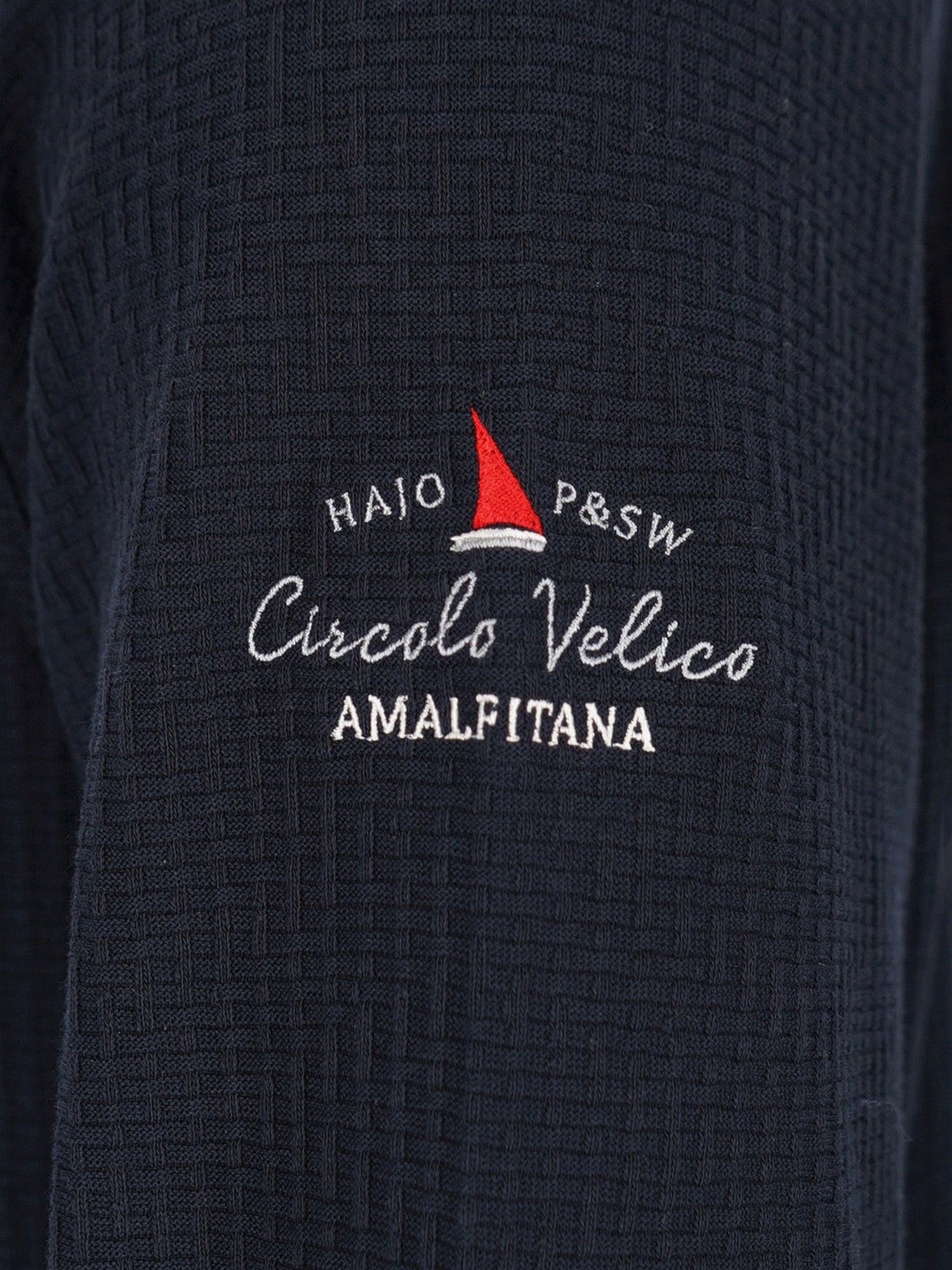 Marineblaue strukturierte Jacke mit rotem Segelboot-Logo und weißem Text.
