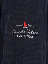 Marineblaue strukturierte Jacke mit rotem Segelboot-Logo und weißem Text.