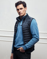 Dunkelblaue Steppweste für Herren über einem hellblauen, langärmeligen Poloshirt.