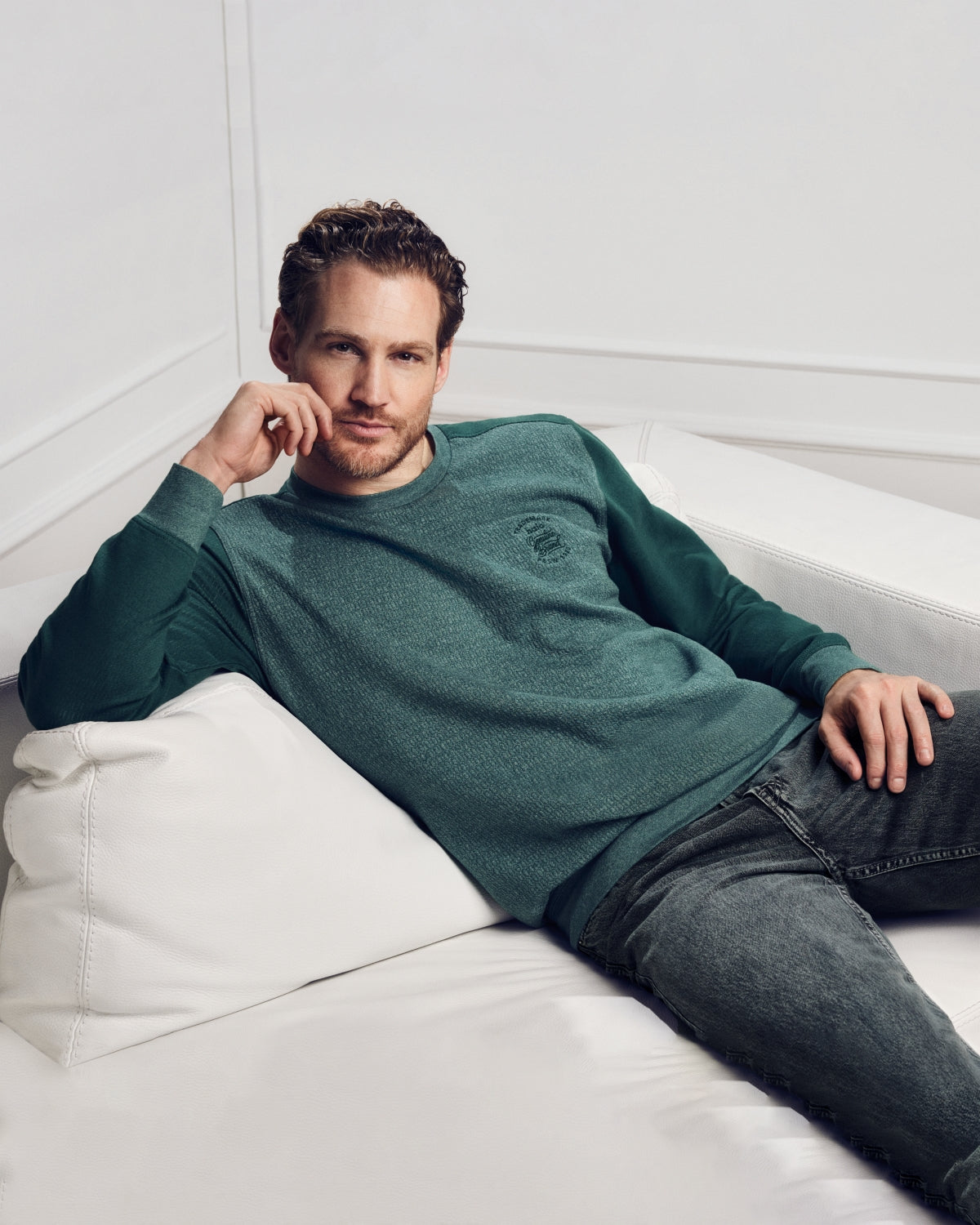 Ein Mann in einem grünen, langärmeligen Hemd und dunklen Jeans.