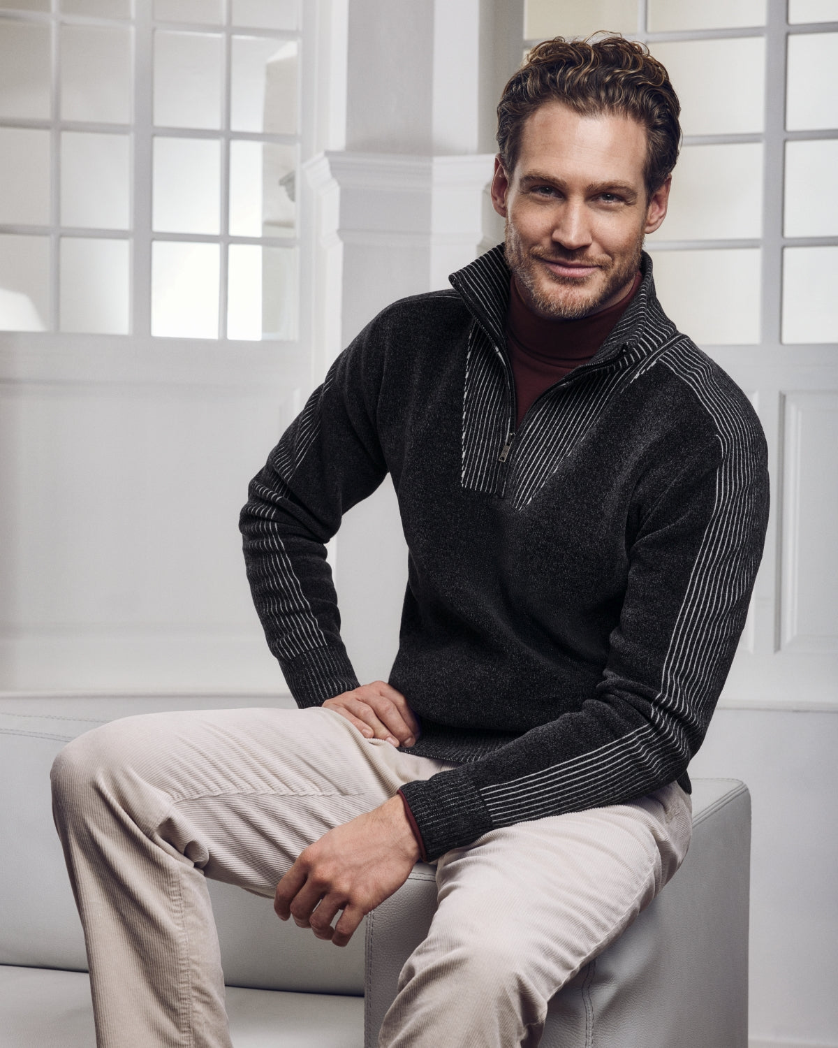 Dunkelgrauer Herrenpullover mit Viertel-Reißverschluss aus Rippenstrick mit weißen Nadelstreifenakzenten.