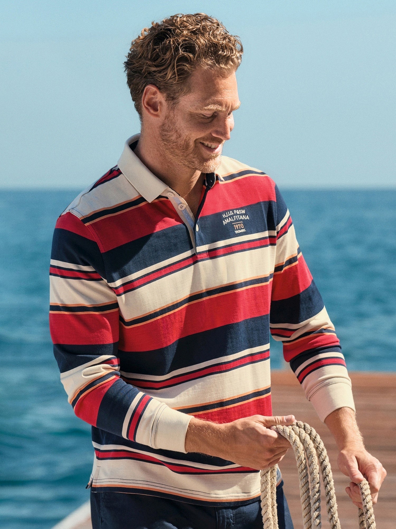 Rot- und marineblaues gestreiftes Poloshirt mit weißem Kragen, Manschetten und Taschen-Details.