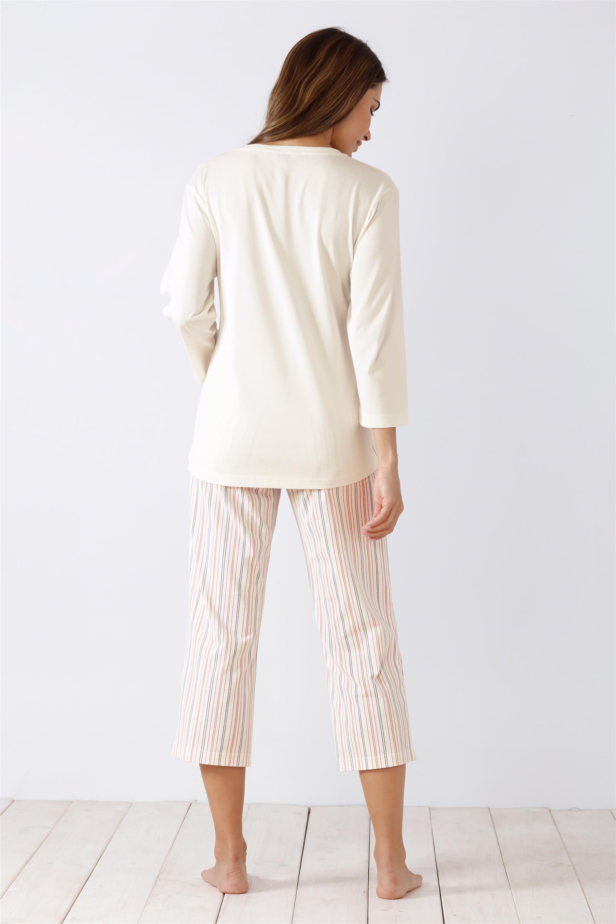 Langärmeliges cremefarbenes Oberteil und gestreifte Caprihose für Damen als Schlafanzug.
