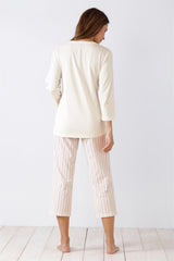 Langärmeliges cremefarbenes Oberteil und gestreifte Caprihose für Damen als Schlafanzug.