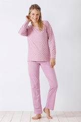 Frau in einem hellrosa langärmeligen Oberteil und passender Hose.