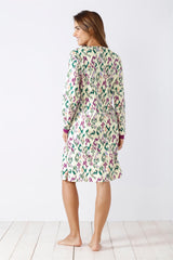 Frau in einem langärmeligen, knielangen gemusterten Nachthemd mit Rüschensaum.