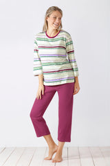 Gestreiftes dreiviertelärmeliges Oberteil einer Frau mit einer einfarbigen beerenfarbenen Caprihose.