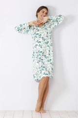 Frau in einem weiß-grünen Nachthemd mit Blattmuster.