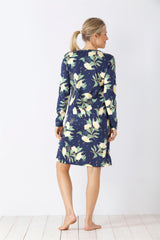 Eine Frau trägt ein knielanges, langärmeliges Nachthemd mit blauem Hintergrund und einem gelben und grünen Blumenmuster.