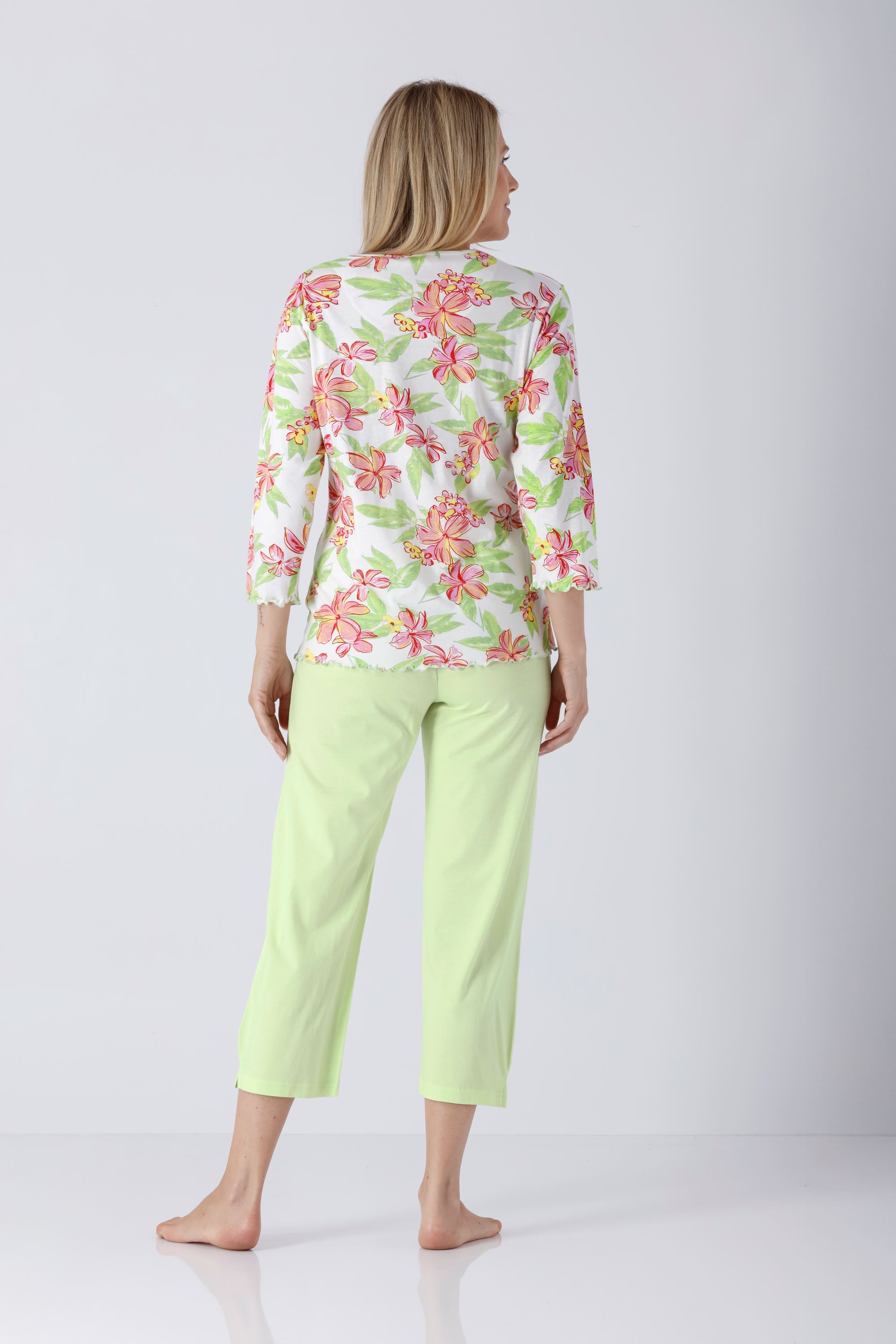 Frau in weißer Bluse mit pink-grünen Blumen und hellgrünen 7/8-Hose aus Premium Cotton/TENCEL™ Modal