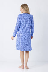 Eine frau trägt ein langärmeliges damen nachthemd mit bündchen in blau mit zartem dunkelblauem floralmuster