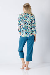 Eine frau trägt einen damen schlafanzug 7 8 aus premium baumwolle tencel modal mit floralem oberteil und türkis caprihose