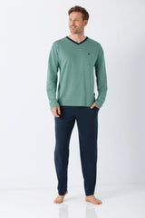 Ein mann trägt den nos herren schlafanzug klima-light® mit teal langarmoberteil und dunklen navy hosen