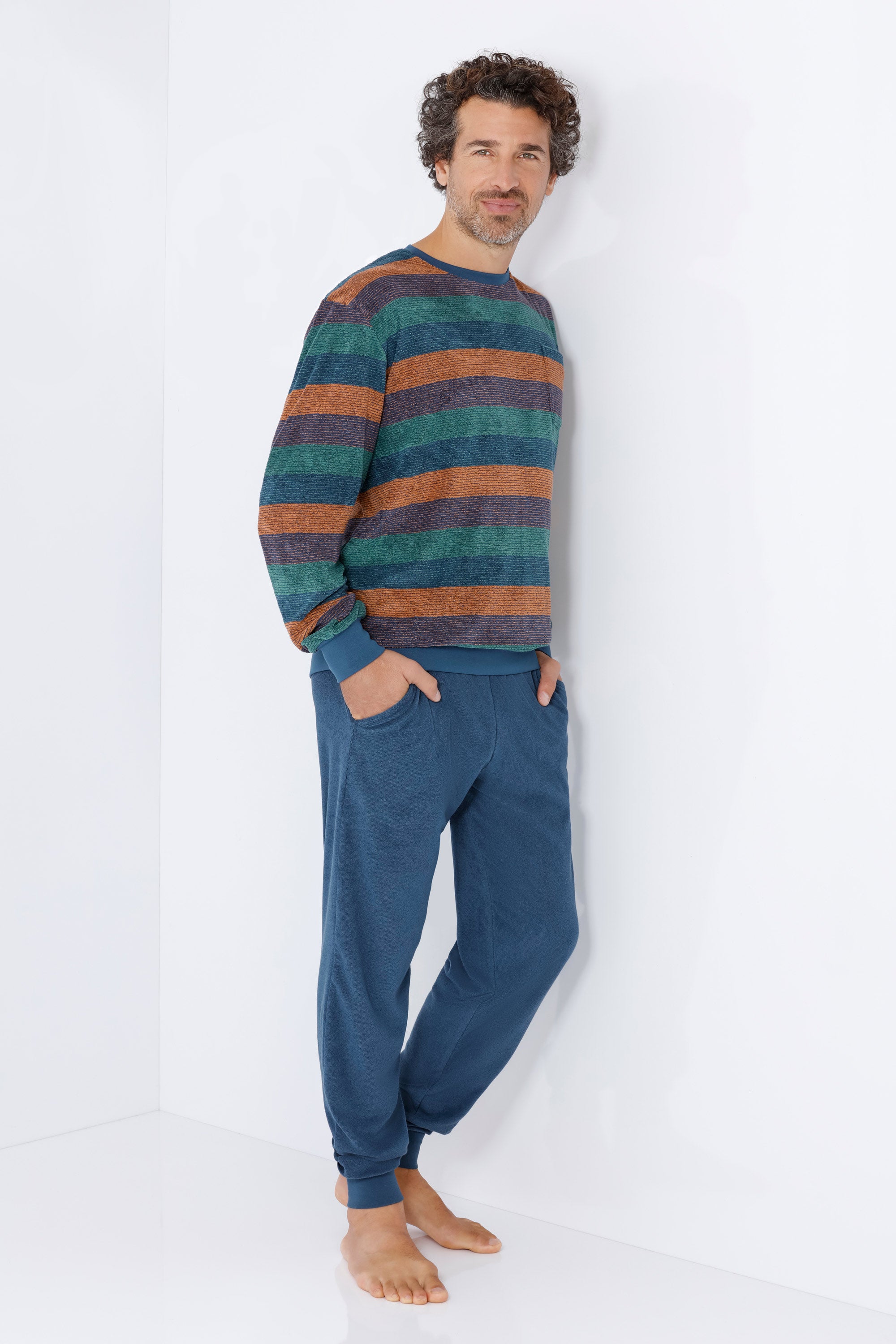 Ein mann trägt einen herren schlafanzug mit bündchen klima-frottee in teal und burnt orange gestreift