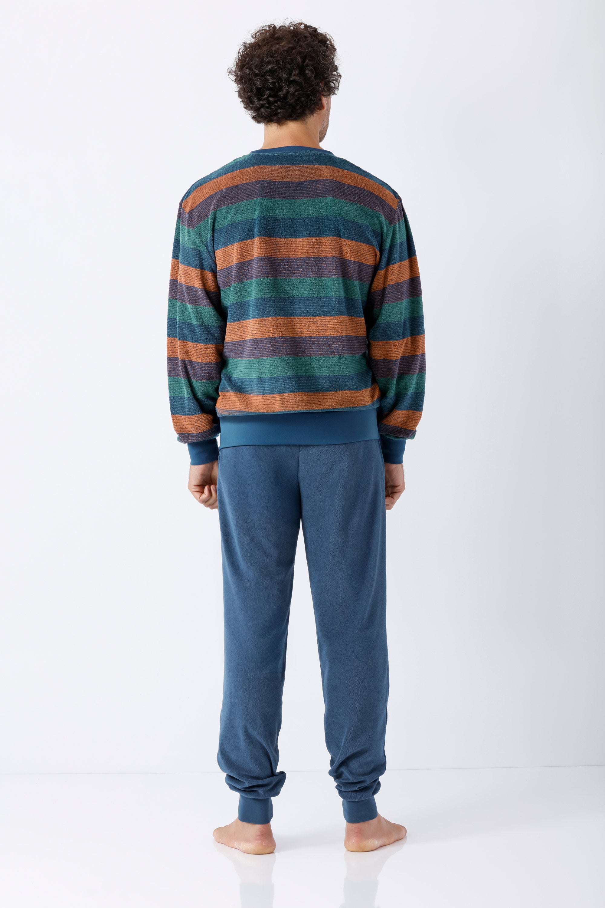 Ein mann trägt einen herren schlafanzug mit bündchen klima-frottee in gestreiftem pullover aus tealgrün und burnt orange mit passenden blauen joggerhosen