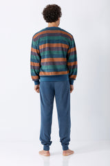 Ein mann trägt einen herren schlafanzug mit bündchen klima-frottee in gestreiftem pullover aus tealgrün und burnt orange mit passenden blauen joggerhosen