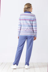 Frau, die ein langärmeliges, gestreiftes Oberteil mit Kragen und eine einfarbige blaue Hose trägt.