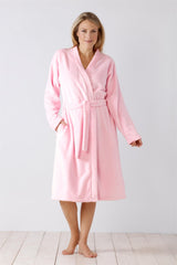 Eine Frau modelliert einen weichen rosa Fleece-Bademantel mit Schnürung und Taschen.