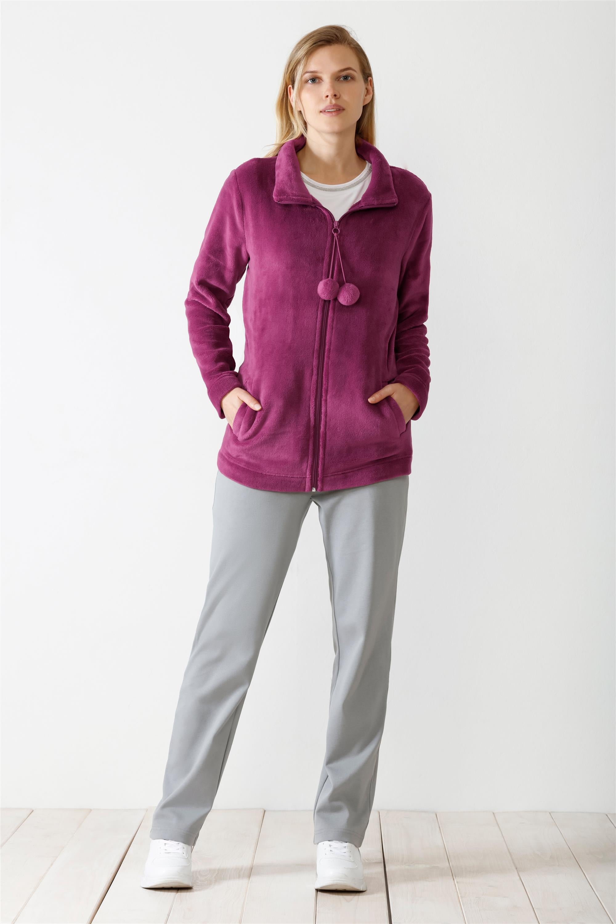 Eine Fleecejacke für Damen mit durchgehendem Reißverschluss in leuchtendem Magenta, mit Stehkragen und zwei dekorativen Bommeln am Halsausschnitt.