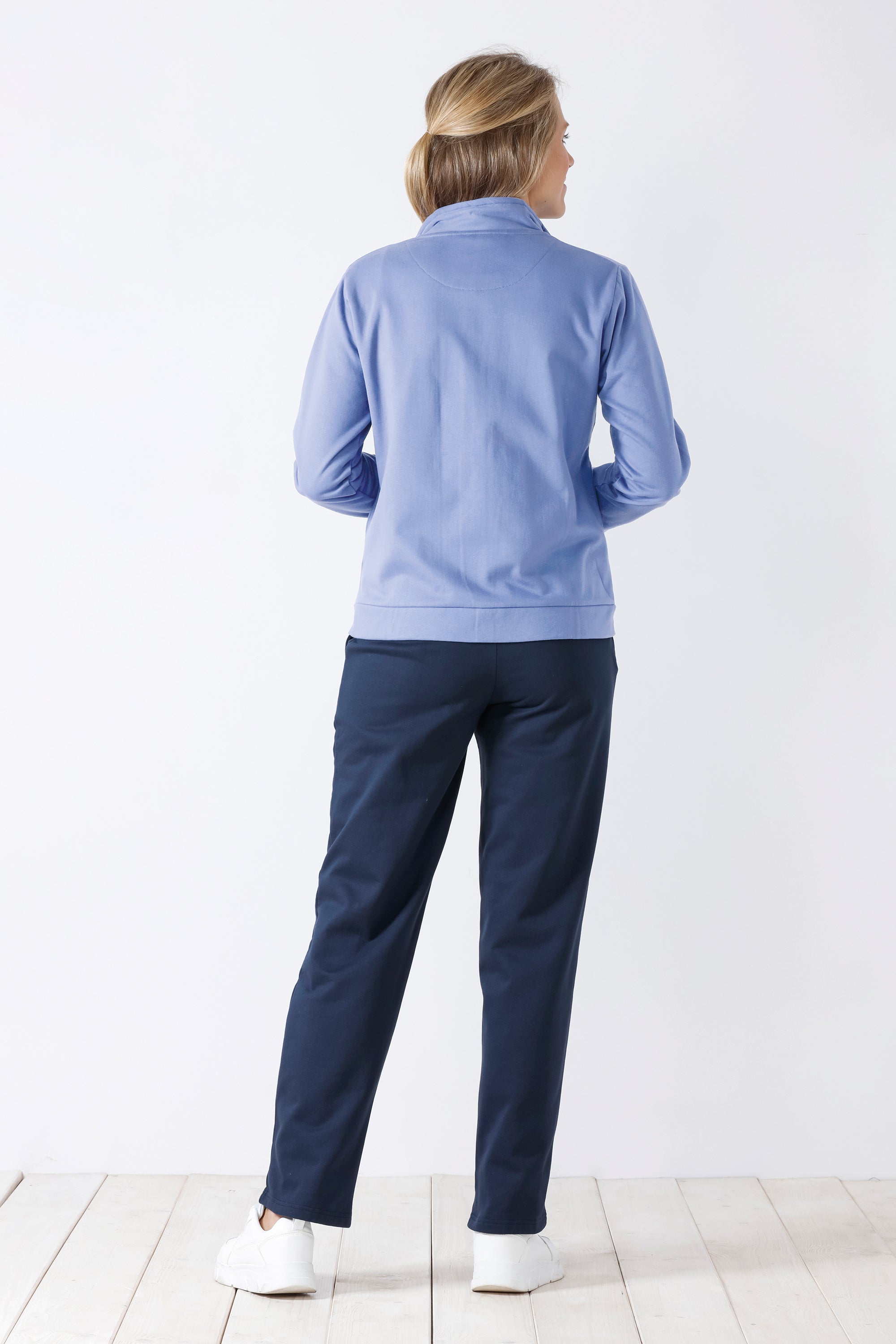 Hellblaues langärmeliges Oberteil mit viertel Reißverschluss und dunkelblaue Hose für Damen.