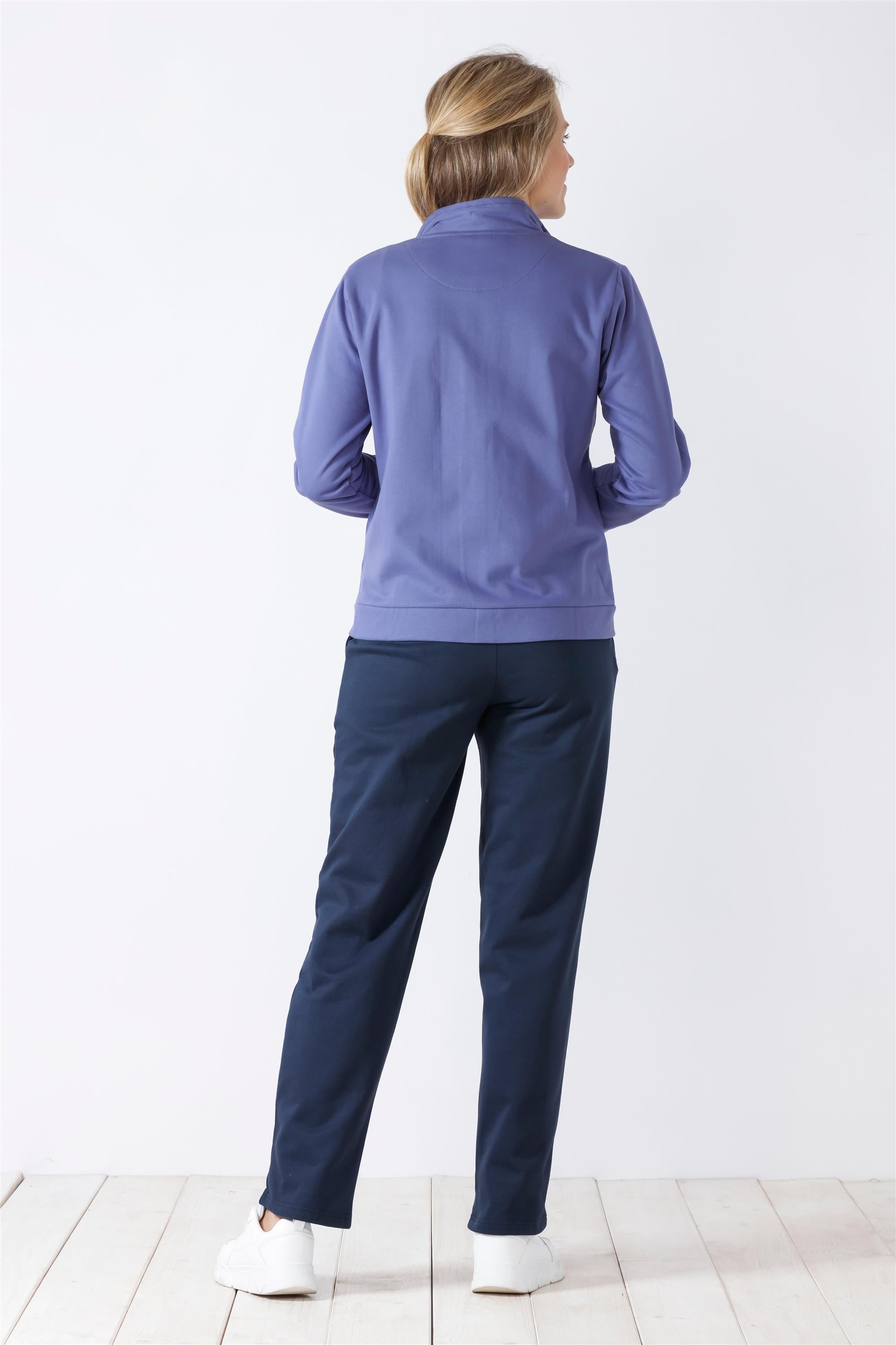 Freizeitkleidung einer Frau, bestehend aus einem langärmeligen lila Oberteil und einer dunkelblauen Hose.