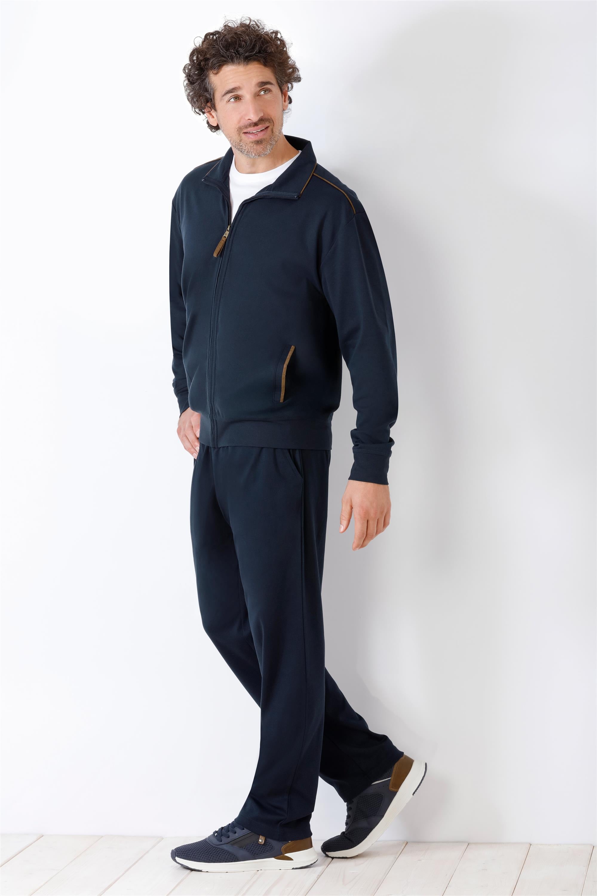 Marineblauer Trainingsanzug für Männer mit durchgehendem Reißverschluss, weißem Unterhemd und Sportschuhen.