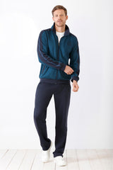 Herren-Trainingsanzug in Petrol und Marineblau mit durchgehendem Reißverschluss, weißem Unterhemd und weißen Sneakers.