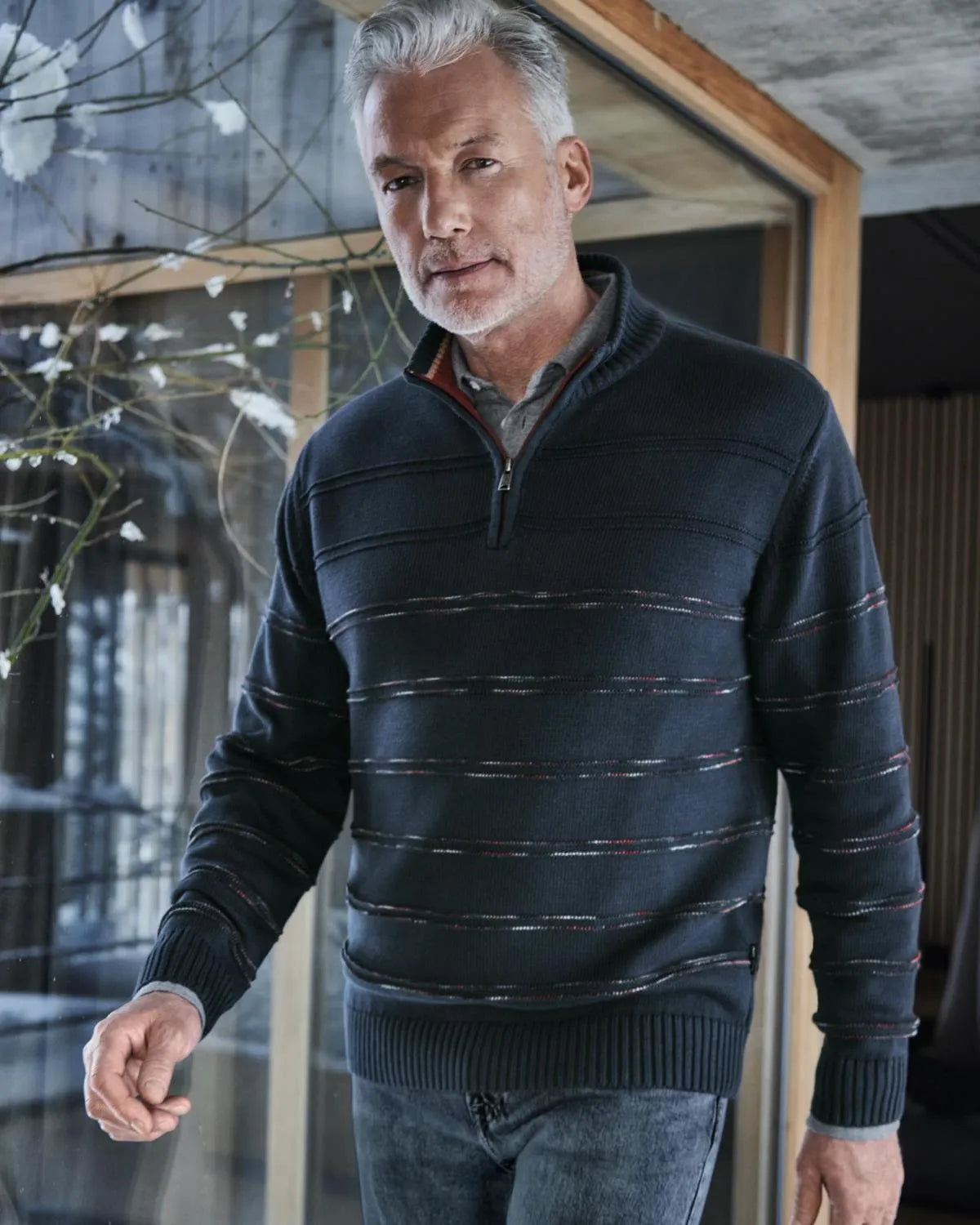 Schwarz-grau gestreifter Pullover mit Viertel-Reißverschluss und gerippten Bündchen und Kragen, wahrscheinlich aus Baumwolle oder einem Polyestergemisch.