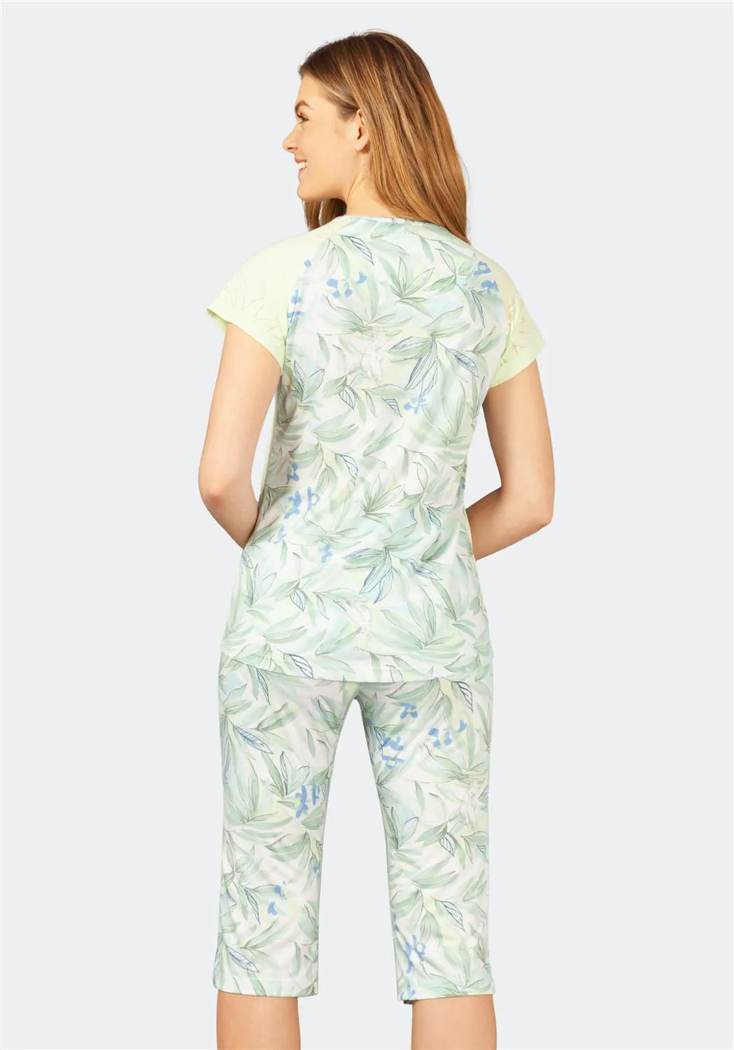 Hellgrünes, mit Blumen bedrucktes Kittel-Set mit Caprihose und kurzärmeligem Oberteil, wahrscheinlich aus einer Uniformlinie für medizinisches oder pflegerisches Personal.