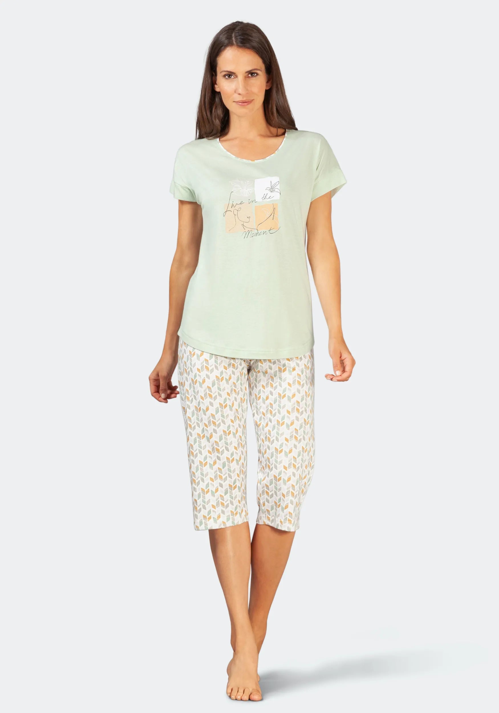 Mintgrünes Kurzarm-T-Shirt mit Katzenmotiv, gepaart mit einer weißen Spitzen-Caprihose.