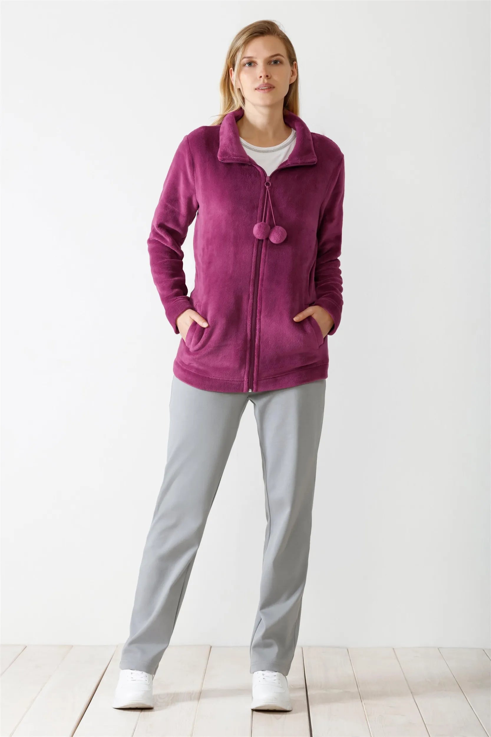 Eine Fleecejacke für Damen mit durchgehendem Reißverschluss in leuchtendem Magenta, mit Stehkragen und zwei dekorativen Bommeln am Halsausschnitt.