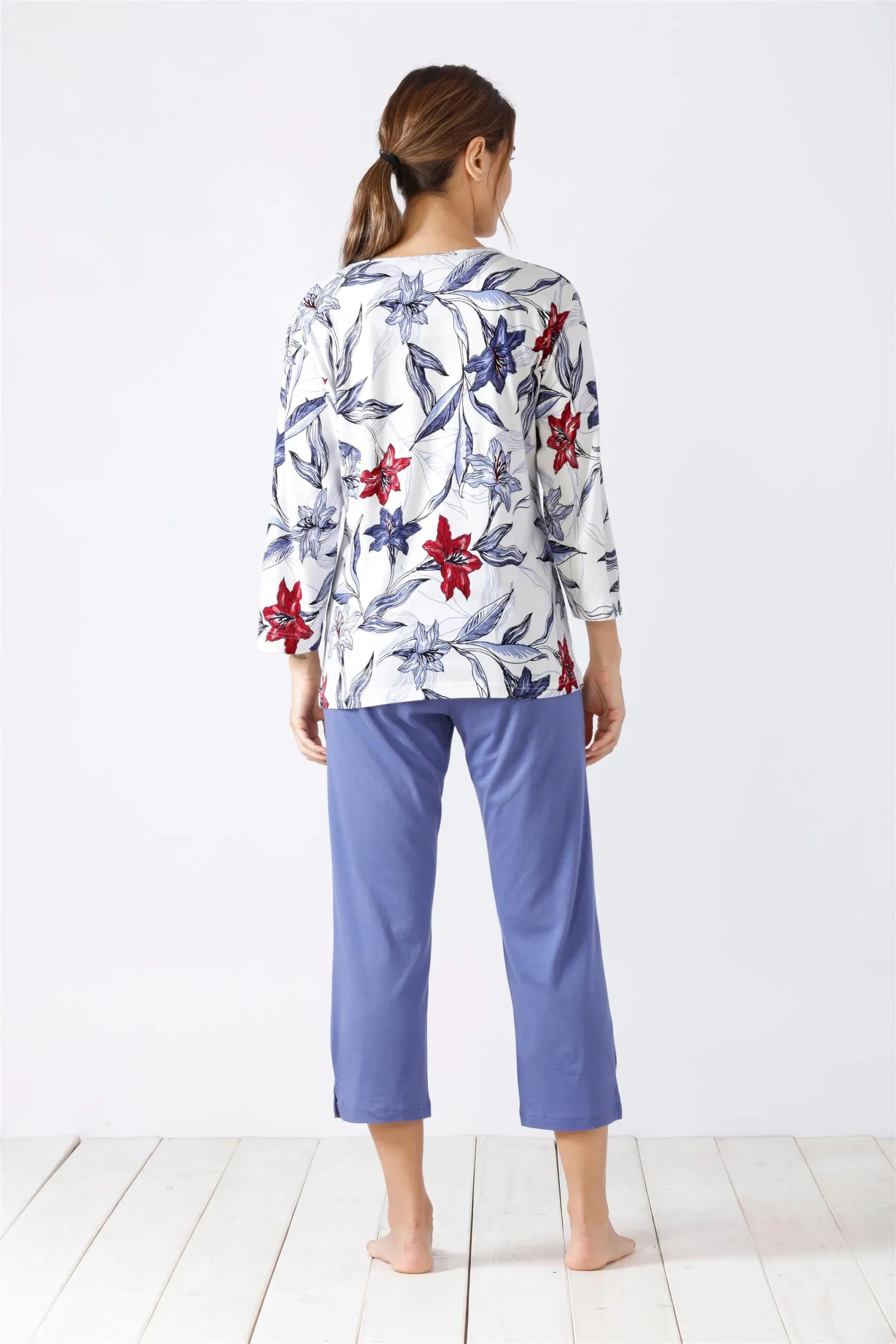 Weißes langärmeliges Oberteil mit Blumendruck und violette Caprihose für Damen als Pyjama-Set.