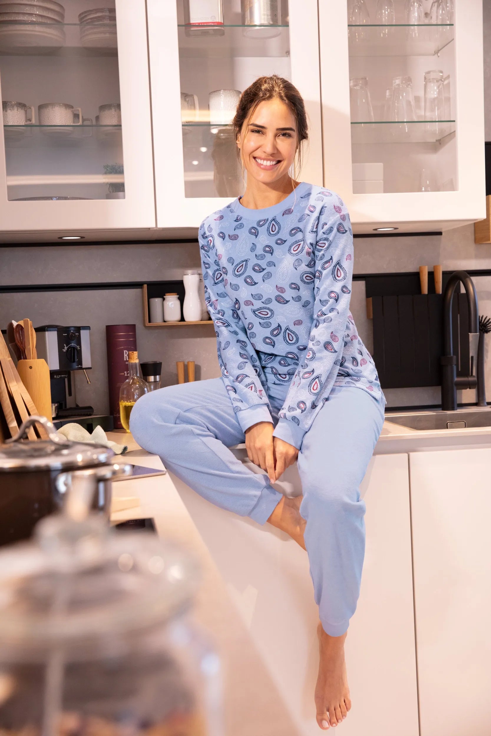 Eine junge Frau in einem hellblauen Pyjama mit Paisleymuster.