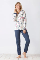 Weißes langärmeliges Damen-Pyjama-Oberteil mit buntem geometrischem Muster und einfarbig blaue Pyjama-Hose.