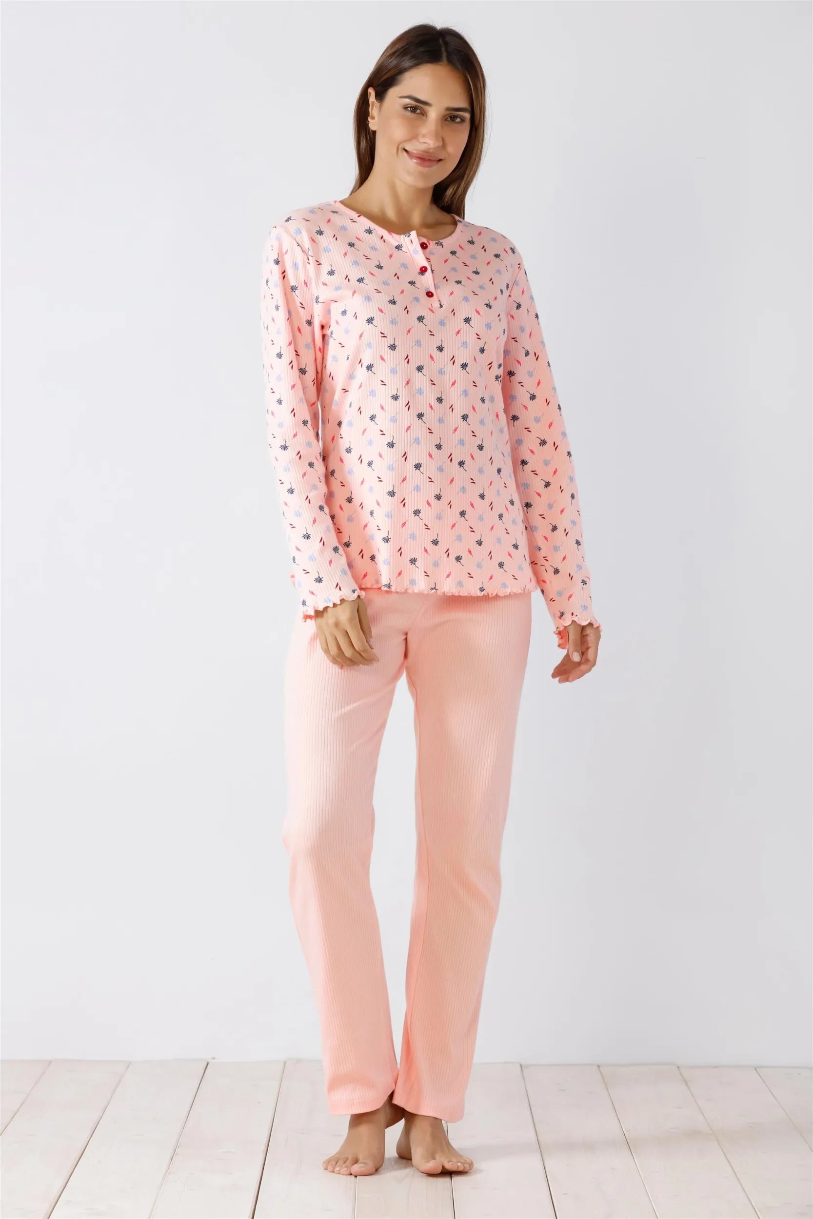 Ein hellrosa, langärmeliges Pyjama-Set mit dezentem, dunklem Blumenmuster und gerüschten Bündchen.