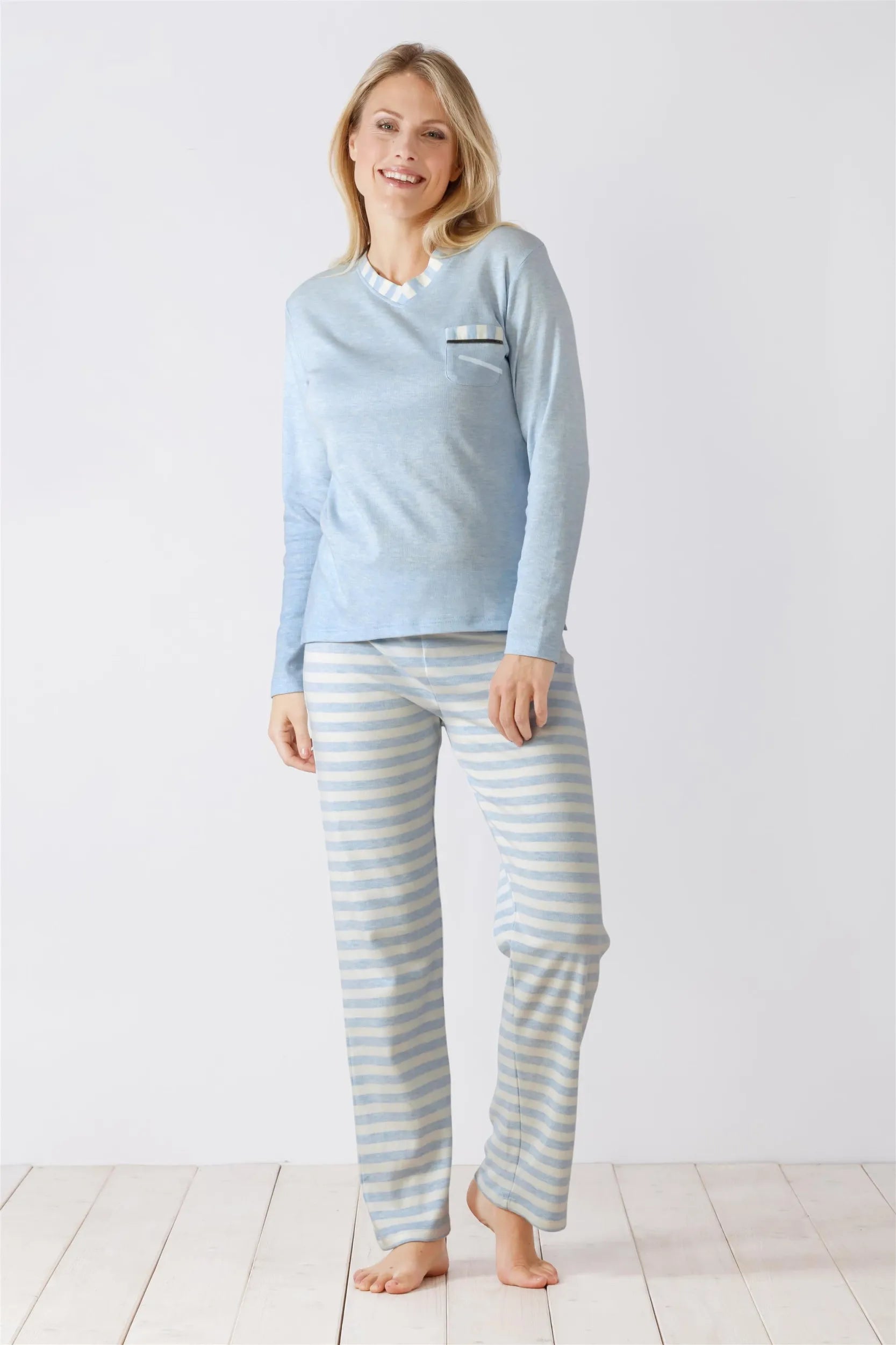 Hellblaues, langärmeliges Damen-Pyjama-Oberteil mit einer kleinen Tasche und gestreifter Pyjama-Hose.