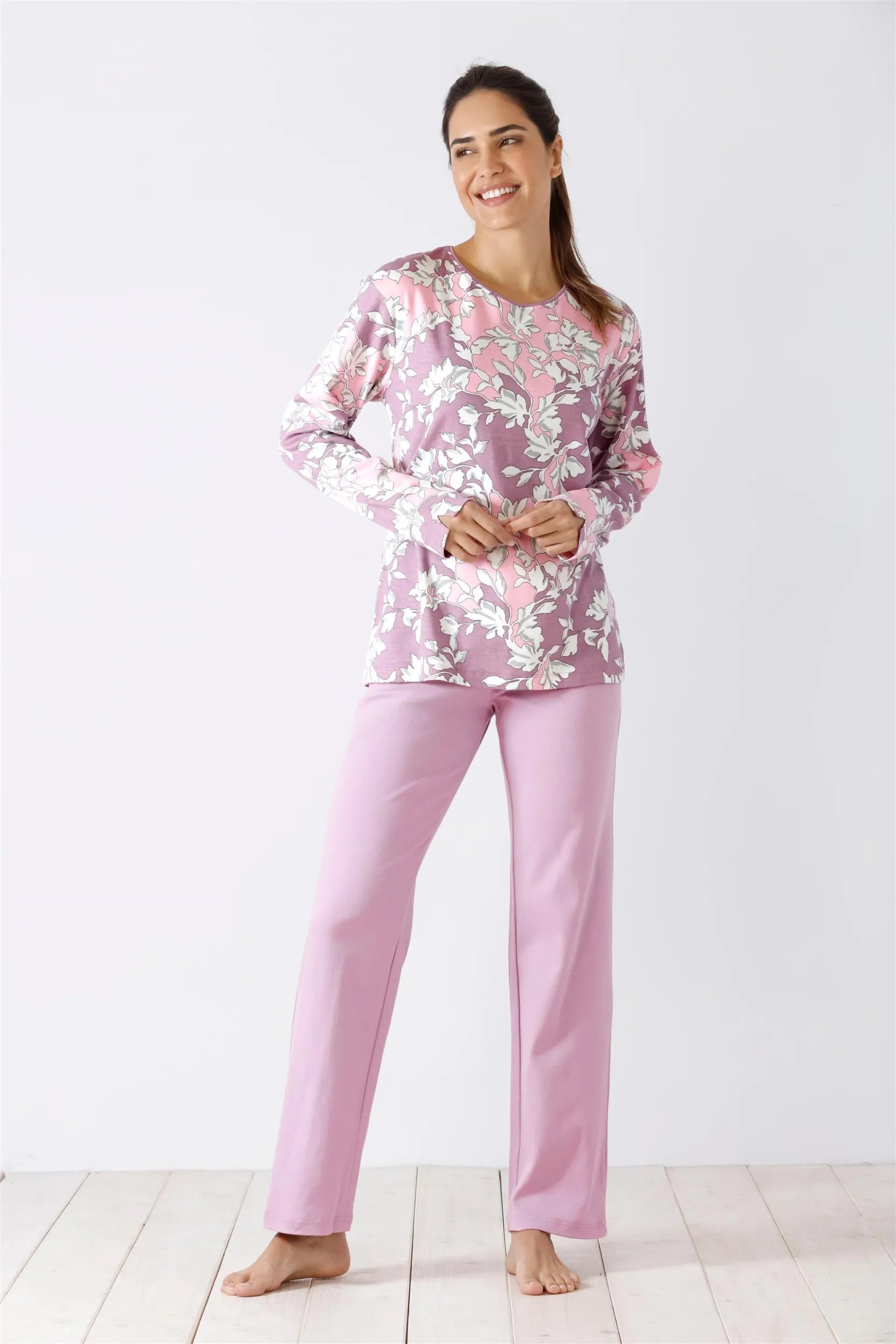 Langärmeliges Pyjamaoberteil mit Blumenmuster und einfarbige rosa Pyjamahose für eine Frau.