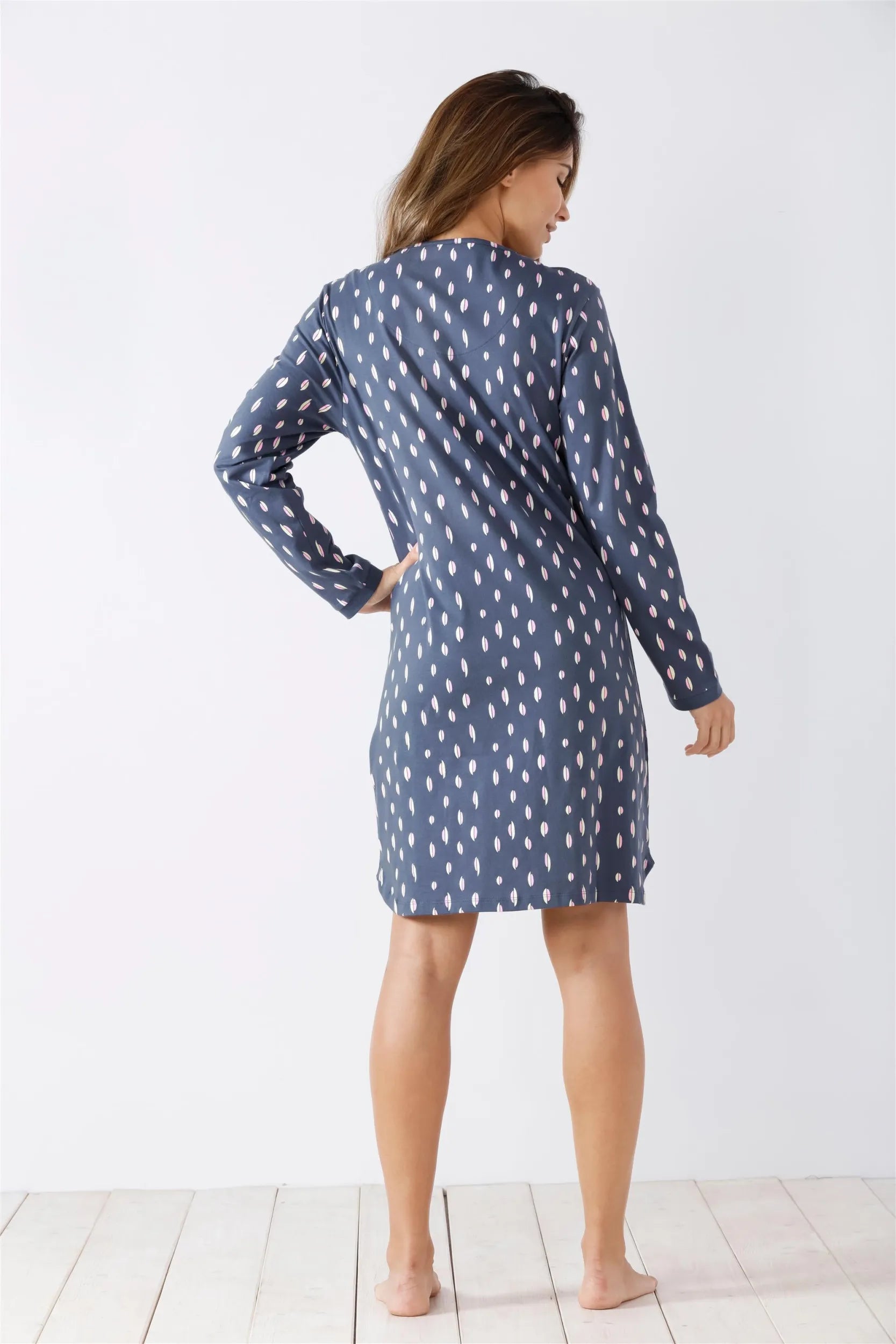 Langärmeliges, kurzes blaues Kleid einer Frau mit weißen, regentropfenartigen Mustern.