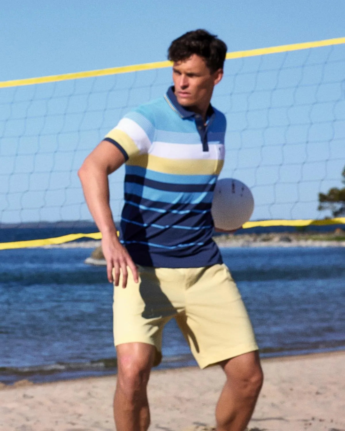 Beachvolleyballnetz mit gelben und schwarzen Maschen, weißer Umrandung und blauem Himmel.